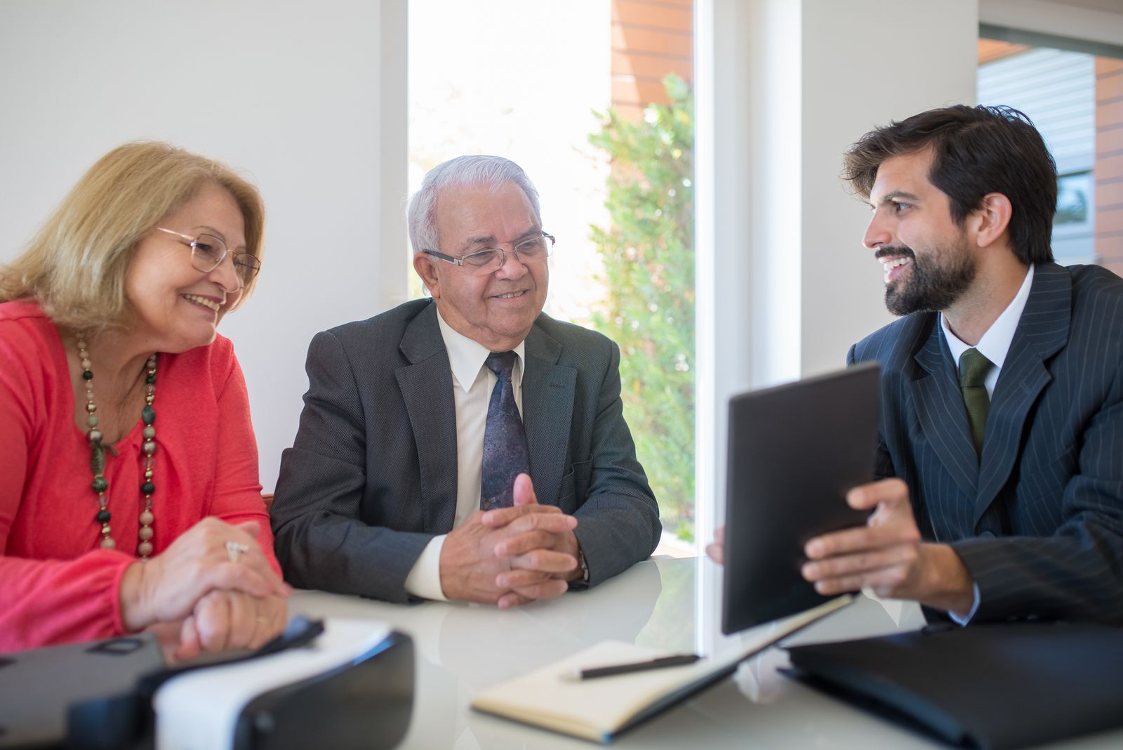 Personne âgée lisant une annonce immobilière avec clés et contrat de viager sur la table